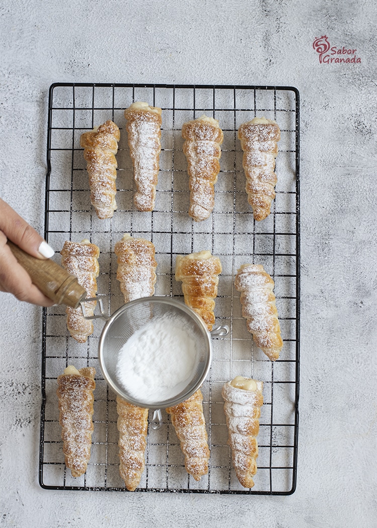 Tercer paso para hacer canutillos rellenos de crema pastelera: se espolvorean con azúcar glass - Sabor Granada